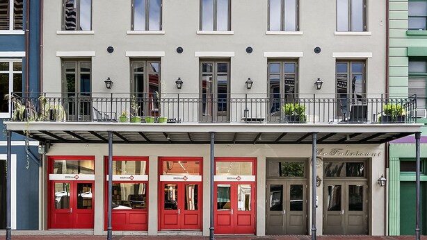 Un edificio de varios pisos con un restaurante en la planta baja llamado "Le Fabrioant" y una fachada roja y blanca.