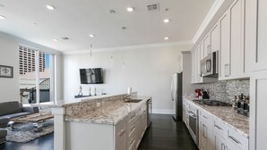 Una cocina moderna con armarios blancos, encimera de granito y electrodomésticos de acero inoxidable.