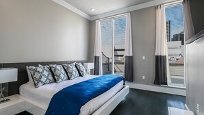 Una habitación de hotel moderna con una cama, un ventilador de techo, una ventana con cortinas y vistas a la ciudad.