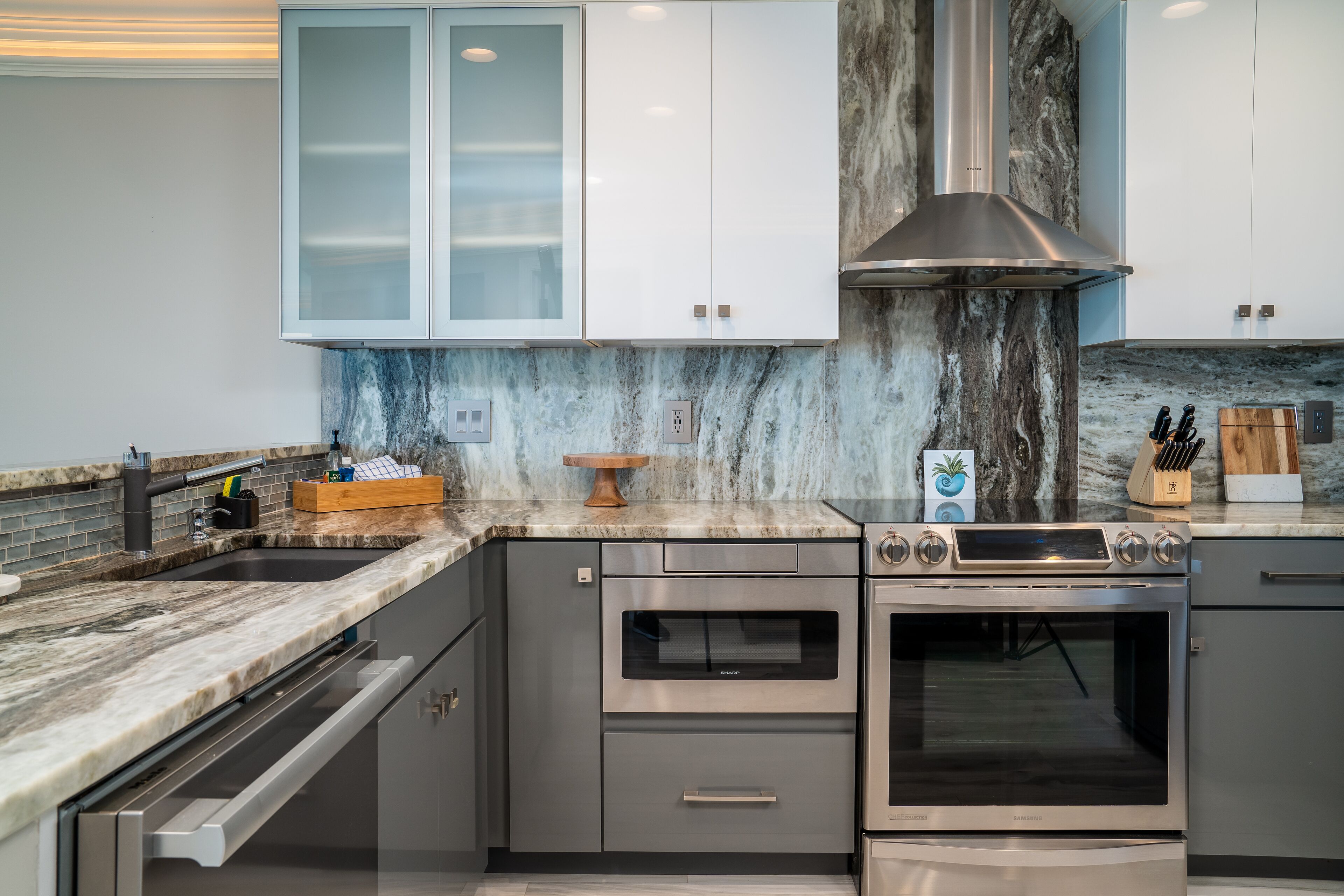 A modern kitchen with stainless steel appliances, marble countertops, and a built-in oven.