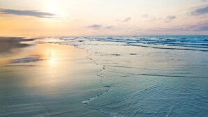 Ein Strand mit ruhigem Meer und blauem Himmel.