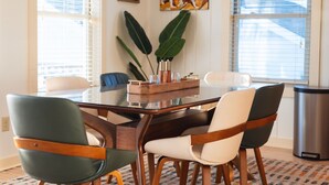 A dining area with a glass table, wooden chairs, and a plant.