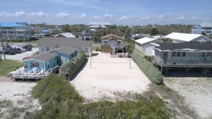 A beachfront property with multiple buildings, including a large house with a porch and a smaller structure with a pool.