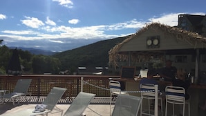 Eine Terrasse mit Liegestühlen, einer Bar und Blick auf Berge.