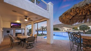 Un patio con piscina, mobiliario exterior y una televisión de pantalla grande.