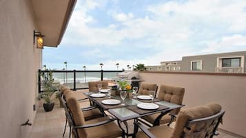 A dining area with a table set for four, overlooking the ocean.