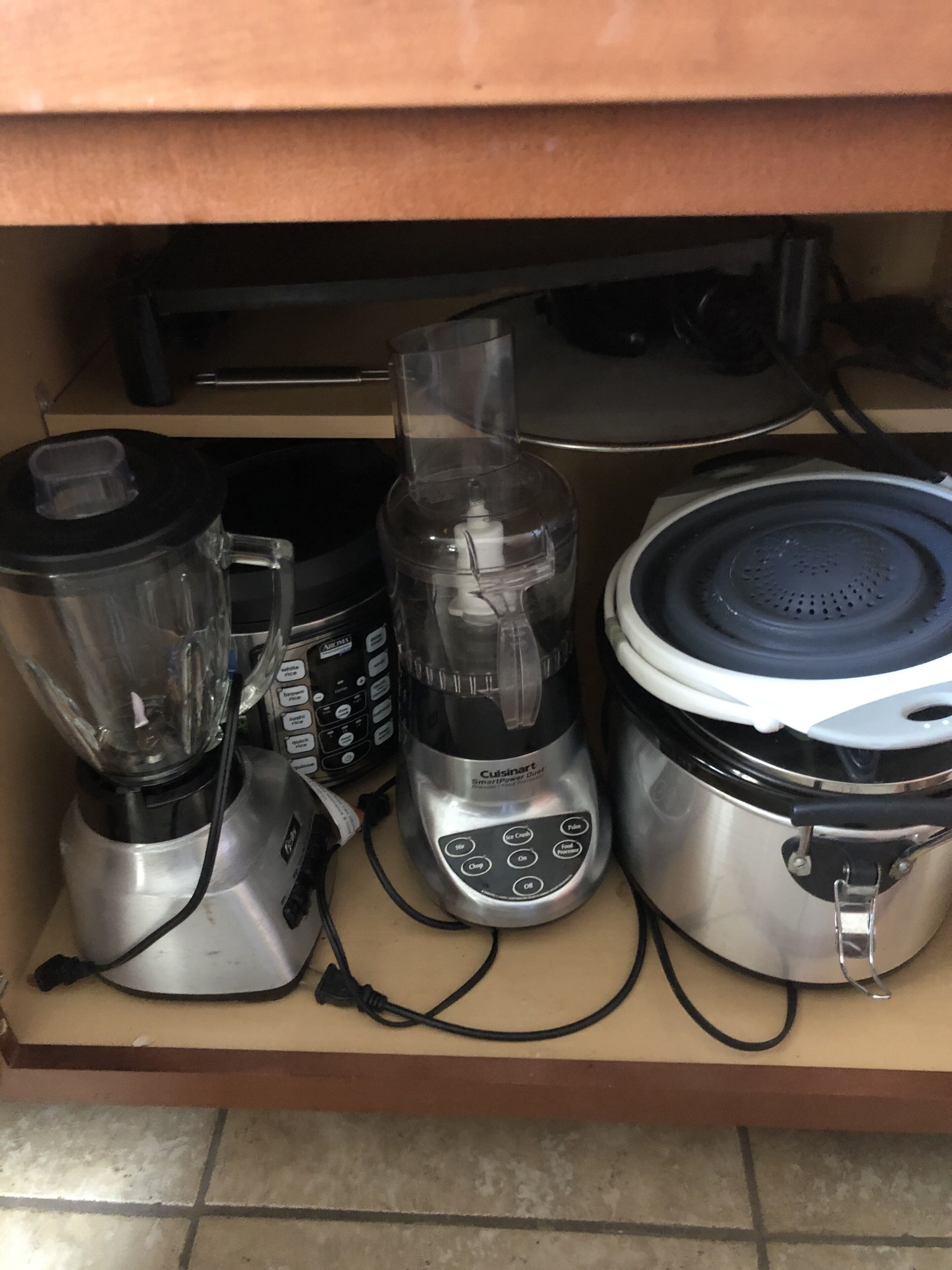 A kitchen drawer containing a blender, a food processor, and a rice cooker.