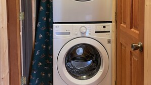 A stacked washer and dryer unit with a green curtain featuring animal prints.