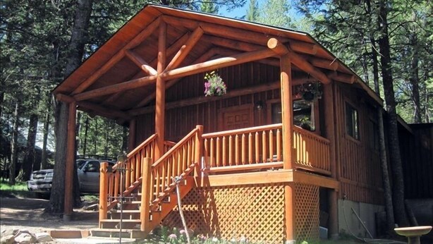 A wooden cabin with a porch, a staircase, and a small garden area.
