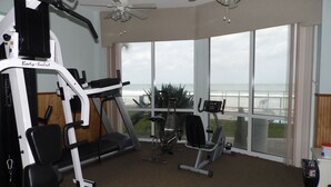 A home gym with exercise equipment, large windows, and a view of the ocean. - Penthouse Suite! Spacious End Corner Unit! 3Bedroom 3 Bath! New Pool 2024 (Daytona Beach)