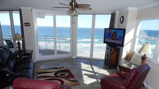 A living room with a view of the ocean, a television, and leather chairs. - Penthouse Suite! Spacious End Corner Unit! 3Bedroom 3 Bath! New Pool 2024 (Daytona Beach)