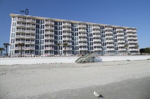 Ein mehrstöckiges Hotel mit Balkonen, direkt am Strand gelegen.