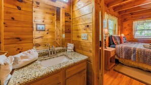 Ein Interieur einer Holzhütte mit Bad, einem Bett und einem Fenster.