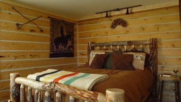 A rustic wooden room with a bed, a wall-mounted light fixture, and a horse silhouette artwork.
