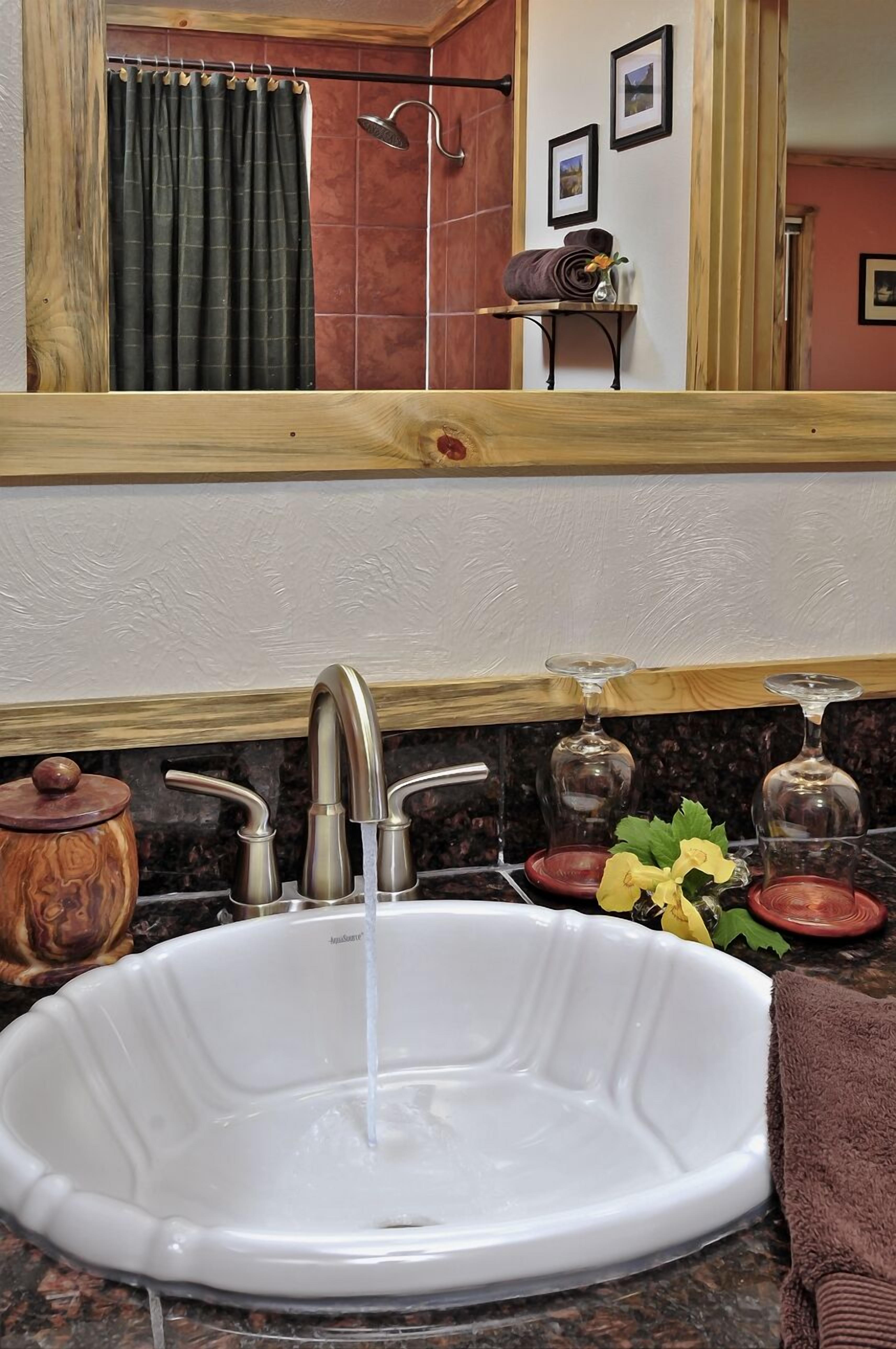 Un baño con lavamanos blanco, tocador de madera y espejo sobre el lavamanos.