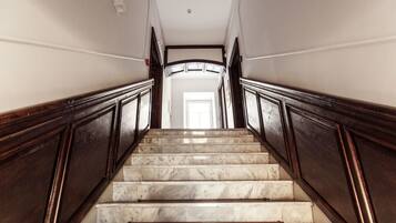 A marble staircase with wooden railings leading to a bright room.