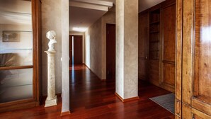 A hallway with wooden flooring, a bust sculpture, and a large wooden cabinet. - Jolly apartments (Vilnius)