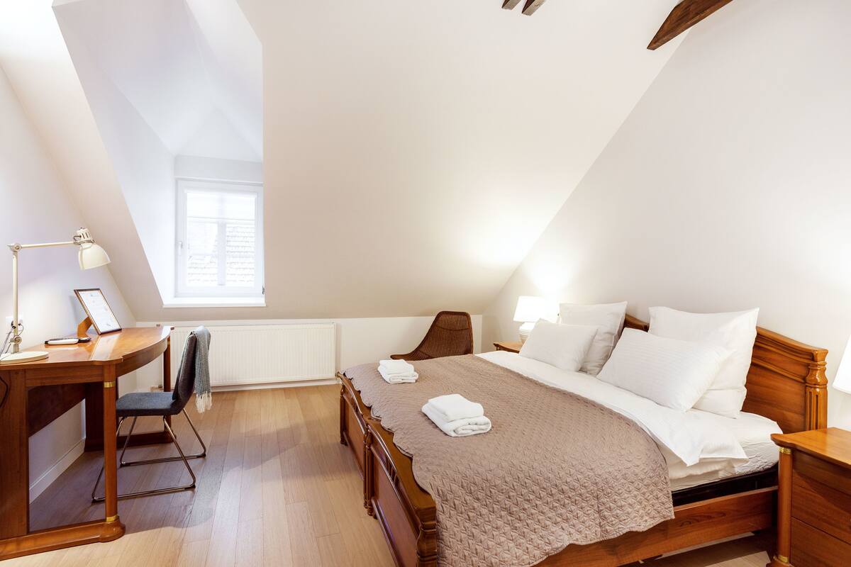 Un dormitorio con cama de madera, un escritorio y una silla.