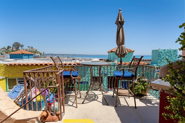 Terraza en la azotea con vistas a la playa, que cuenta con mobiliario exterior y una estatua.