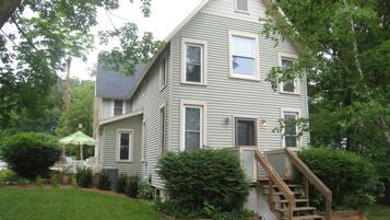 A two-story house with a front porch, a wooden staircase, and a well-maintained lawn.