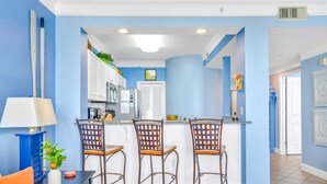 Une cuisine avec un mur d’accent bleu, des armoires blanches et un coin bar équipé de trois tabourets.