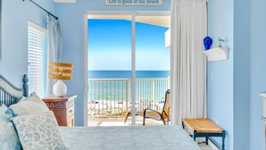 Une chambre avec vue sur la plage, comprenant un lit, une chaise et une petite table.