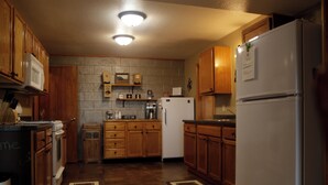 A kitchen with wooden cabinets, a white refrigerator, and a coffee bar.