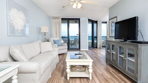 Un salon comprenant un canapé, une table basse, un téléviseur et un balcon avec vue.