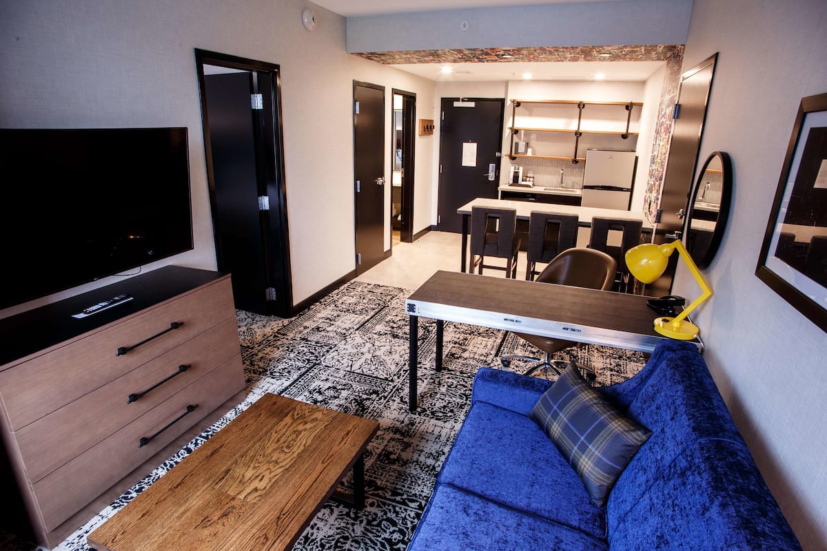 Ein gemütlicher Wohnbereich mit Fernseher, Sofa, Couchtisch und einer kleinen Essecke.