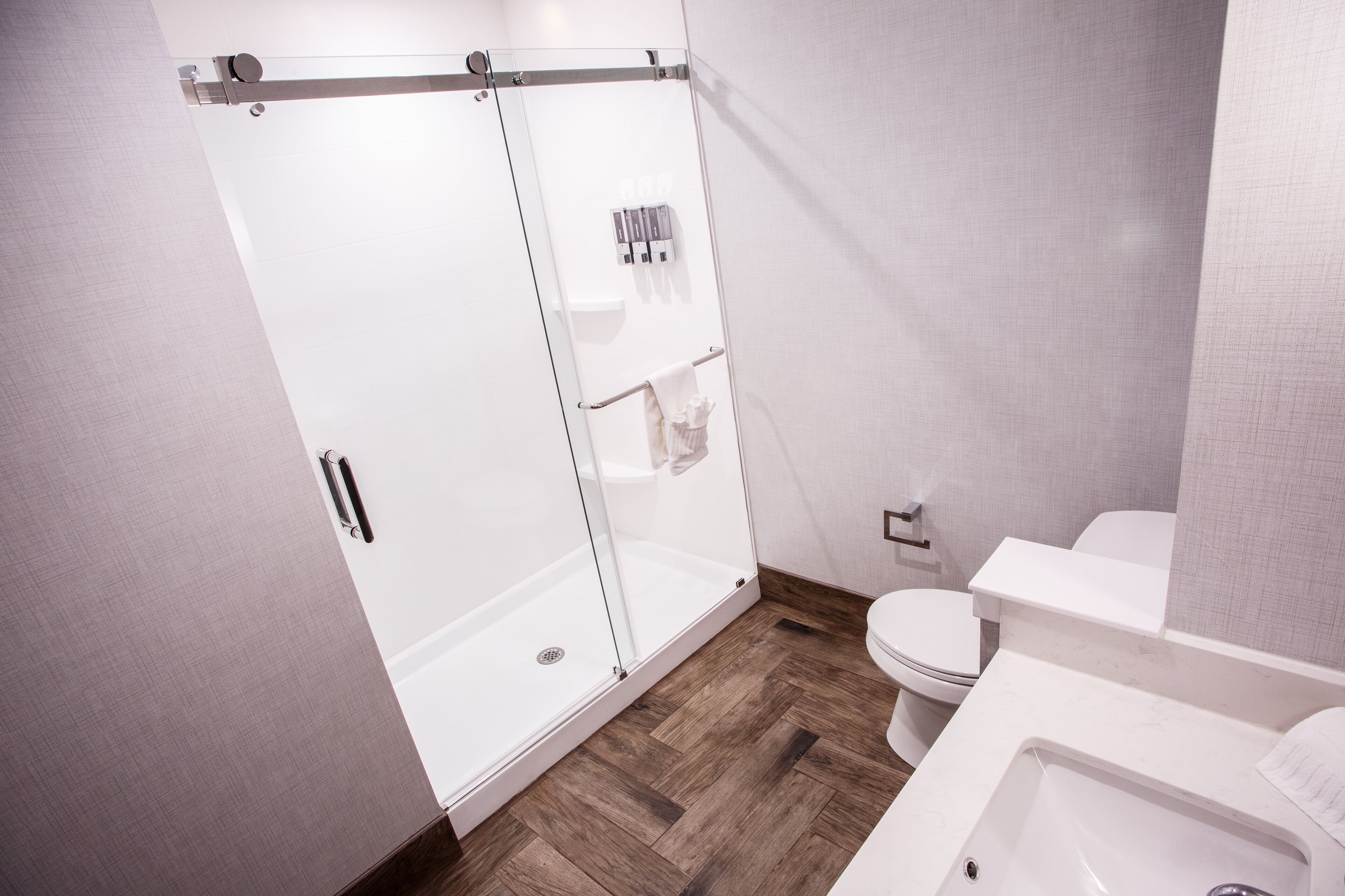 A modern bathroom with a glass-enclosed shower, a white toilet, and a sink.