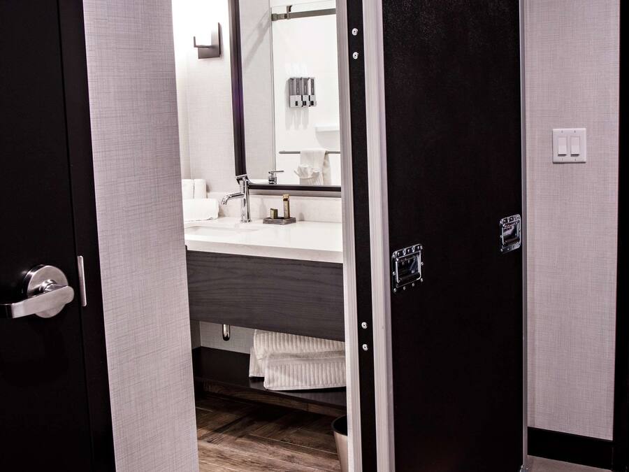 A modern bathroom with a dark door, a white sink, and a mirror.