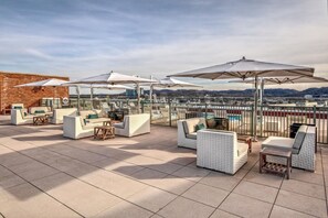 En tagterrasse med udendørs siddepladser og parasoller med udsigt over bybilledet.