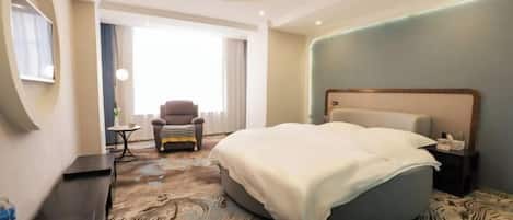 A hotel room with a large bed, a desk, a chair, and a view of the outdoors.