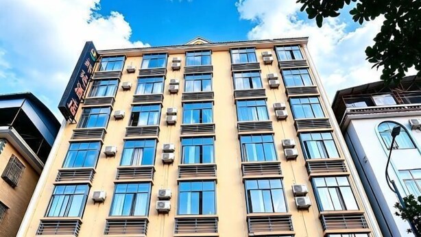 A multi-story building with air conditioning units, large windows, and a clear sky. - Langting Boutique Hotel (Ruili)