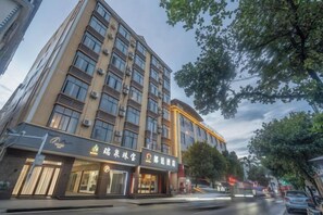 A multi-story hotel with a modern facade, featuring a ground-level restaurant and a visible entrance. - Langting Boutique Hotel (Ruili)