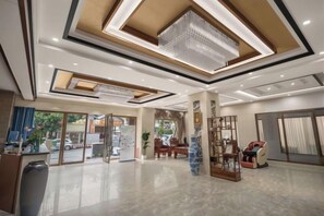 Un hall de hotel con mostrador de recepción, zona de estar y amplios ventanales.