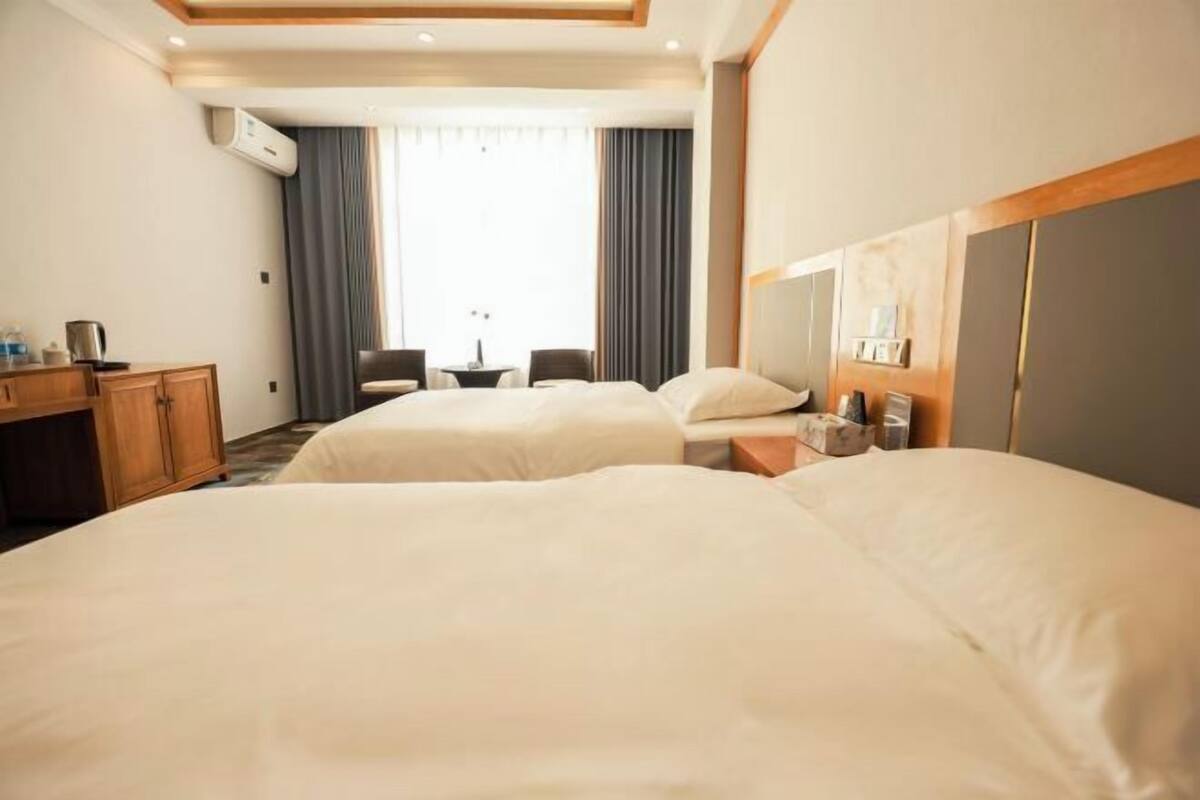 Hotellihuone, jossa on kaksi sänkyä, työpöytä, tuoli ja pieni pöytä.