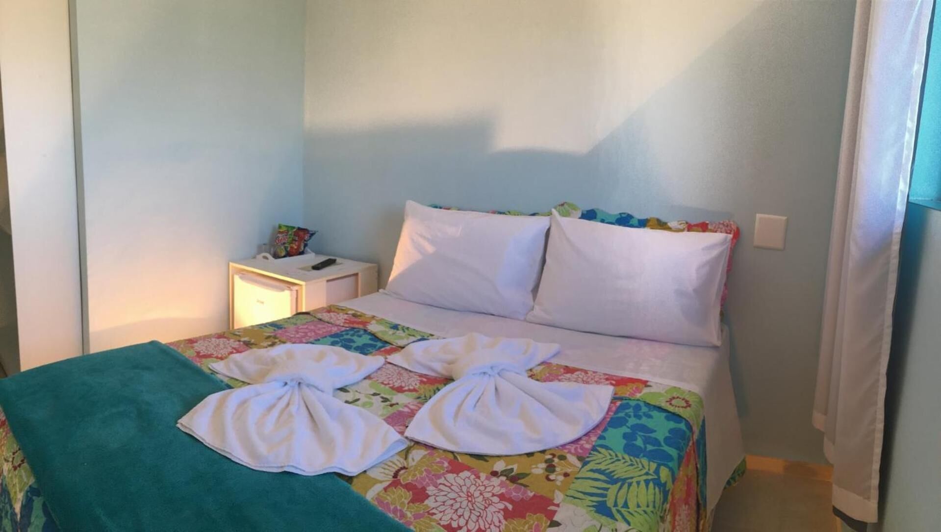 Un dormitorio con una cama, almohadas, una mesita de noche y una colcha.