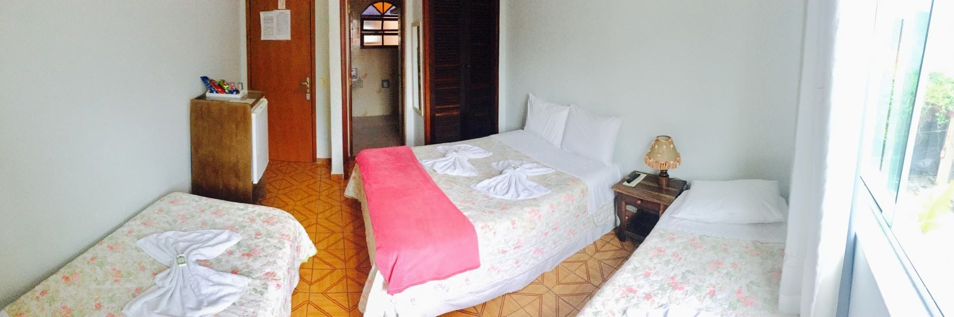 Une chambre d’hôtel avec deux lits simples, une table de chevet en bois, une petite table et une fenêtre.