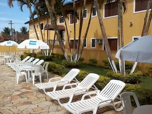 Una piscina al aire libre, sombrillas, sillones reclinables de piscina