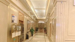 A hotel corridor with a polished marble floor, a green directional sign, and a decorative ceiling. - Vienna Hotel (Dongguan)
