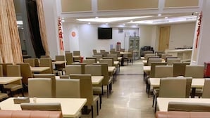 A spacious dining area with multiple tables and booths, a flat-screen TV mounted on the wall, and a clean, tiled floor. - Vienna Hotel (Dongguan)