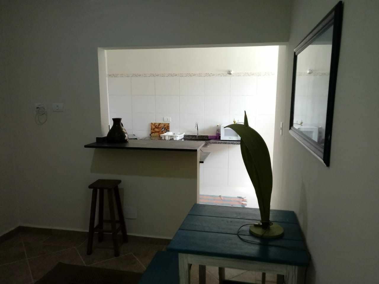 Et lille køkken med et vindue, en skammel og et bord med en plante.