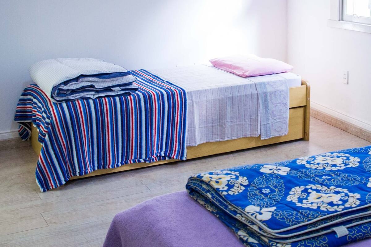 Een kamer met twee bedden, waarvan één met een gestreept laken en de ander met een bloemenprint.
