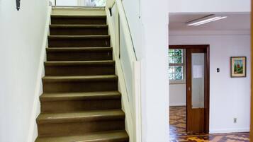 A staircase with a handrail, a light fixture, and a patterned floor.
