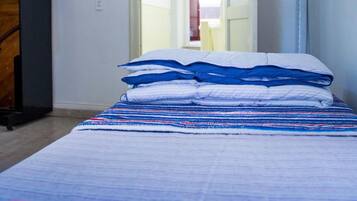 Een slaapkamer met een bed, een kledingkast en een deur naar een andere kamer.