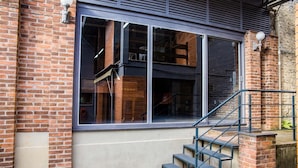 Een bakstenen gebouw met een groot raam en een trap naar een hoger gelegen verdieping.