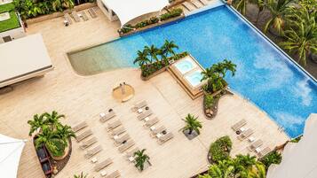 Uma área de piscina no terraço com espreguiçadeiras, palmeiras e uma pequena banheira de hidromassagem.