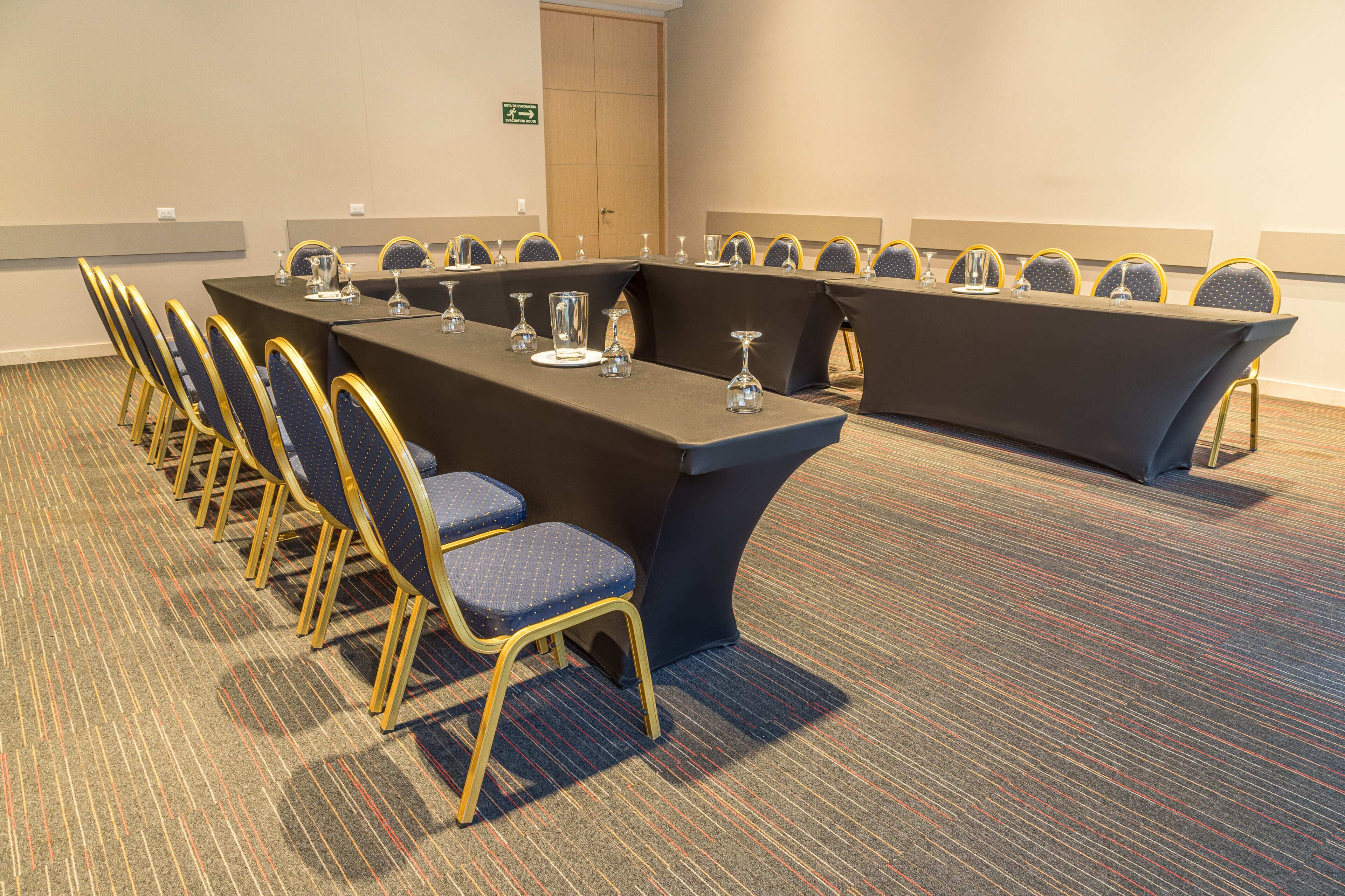 A conference room with a long table and chairs, carpeted floor, and a door in the background.