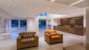 A spacious lobby with a reception desk, two wicker sofas, and a large window offering a view of the outdoors. - Hotel Irotama Reservado (Santa Marta)